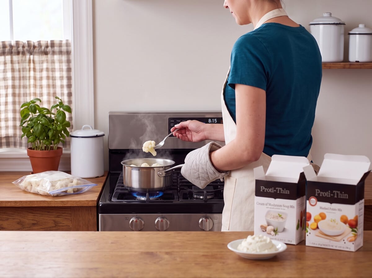 Step 1: lifting a cauliflower floret with a fork from a steaming pot on a gas stove